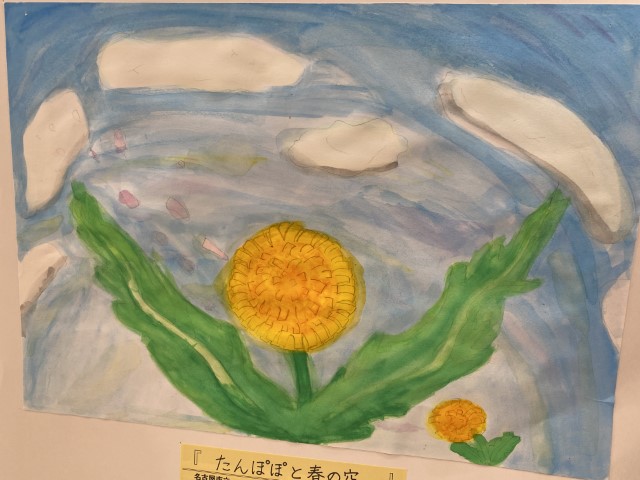 student artwork of yellow dandelions with green leaves with a blue background with white clouds.