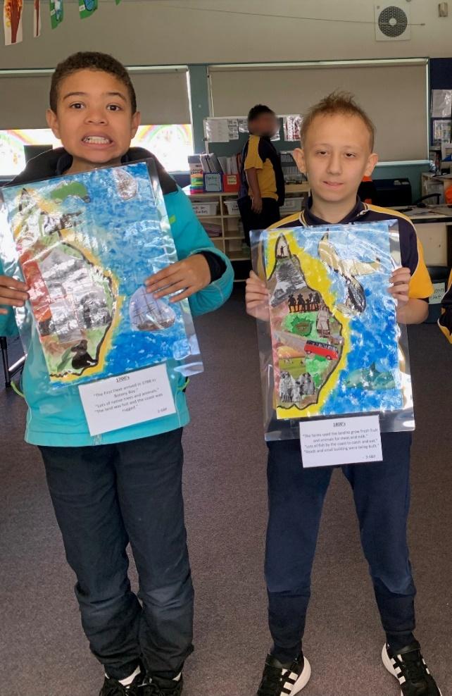 Two boys each hold one of the ‘Changing History’ collages that depict the changing coastline of eastern Australia.
