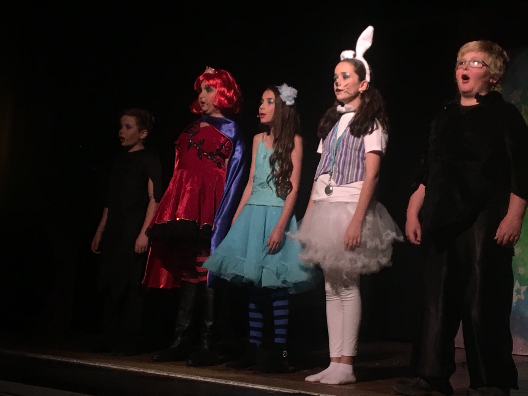 5 drama students on stage dressed in outfits from Alice in Wonderland