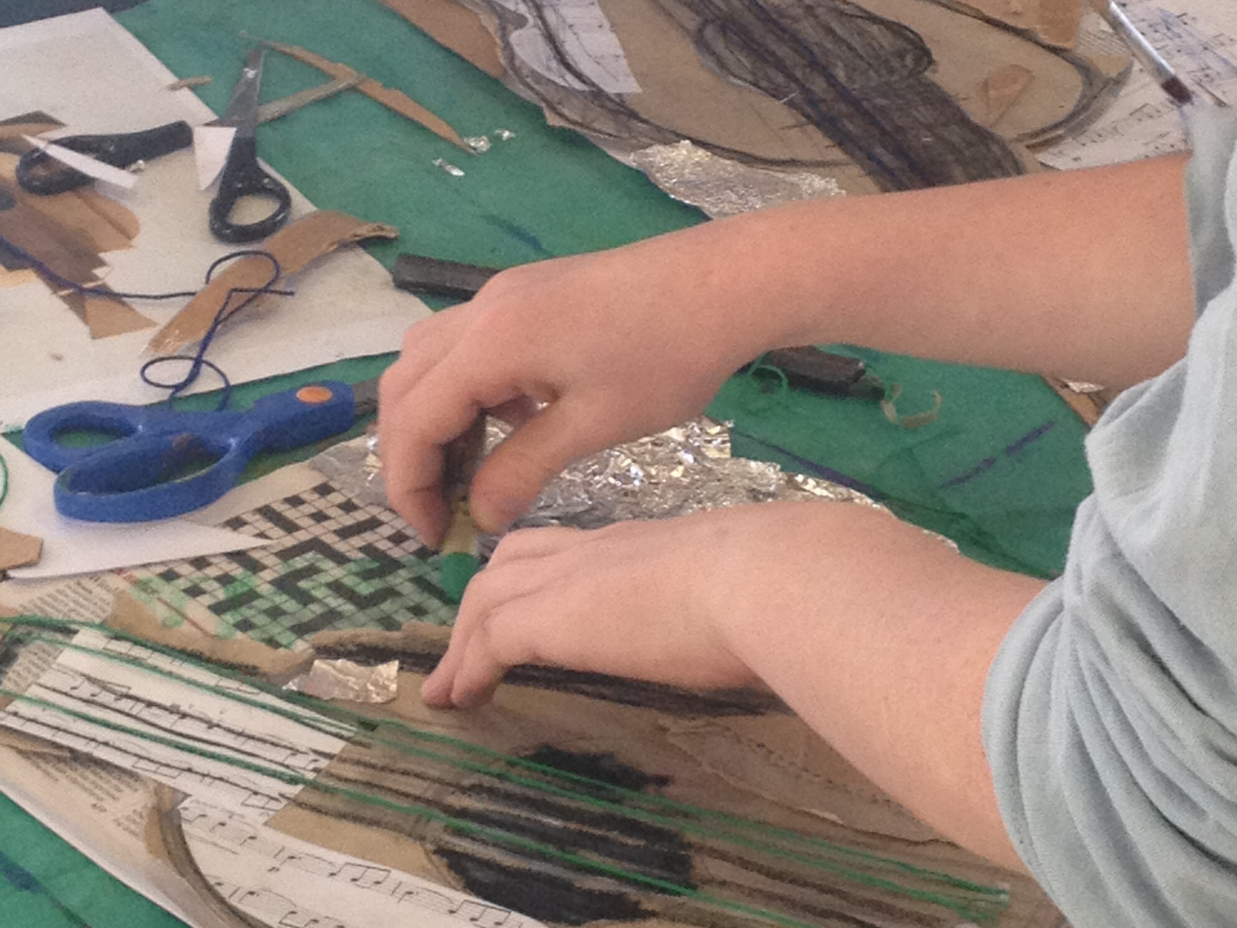 student hands at table creating artwork 