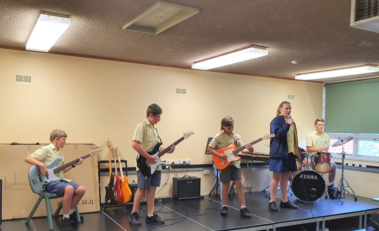 High school students performing in a rock band inside a classroom