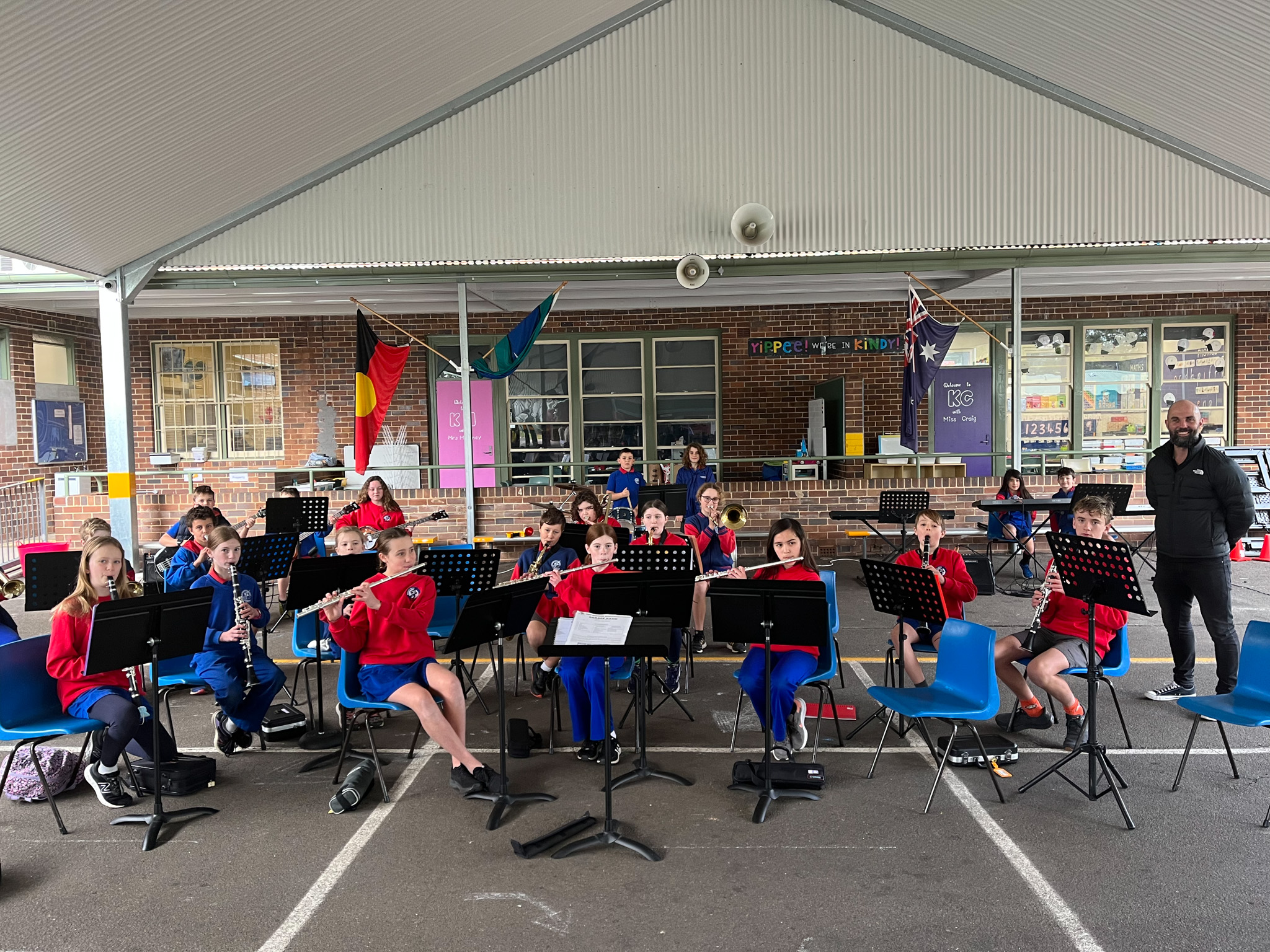 The school band playing under cover on the school playground.