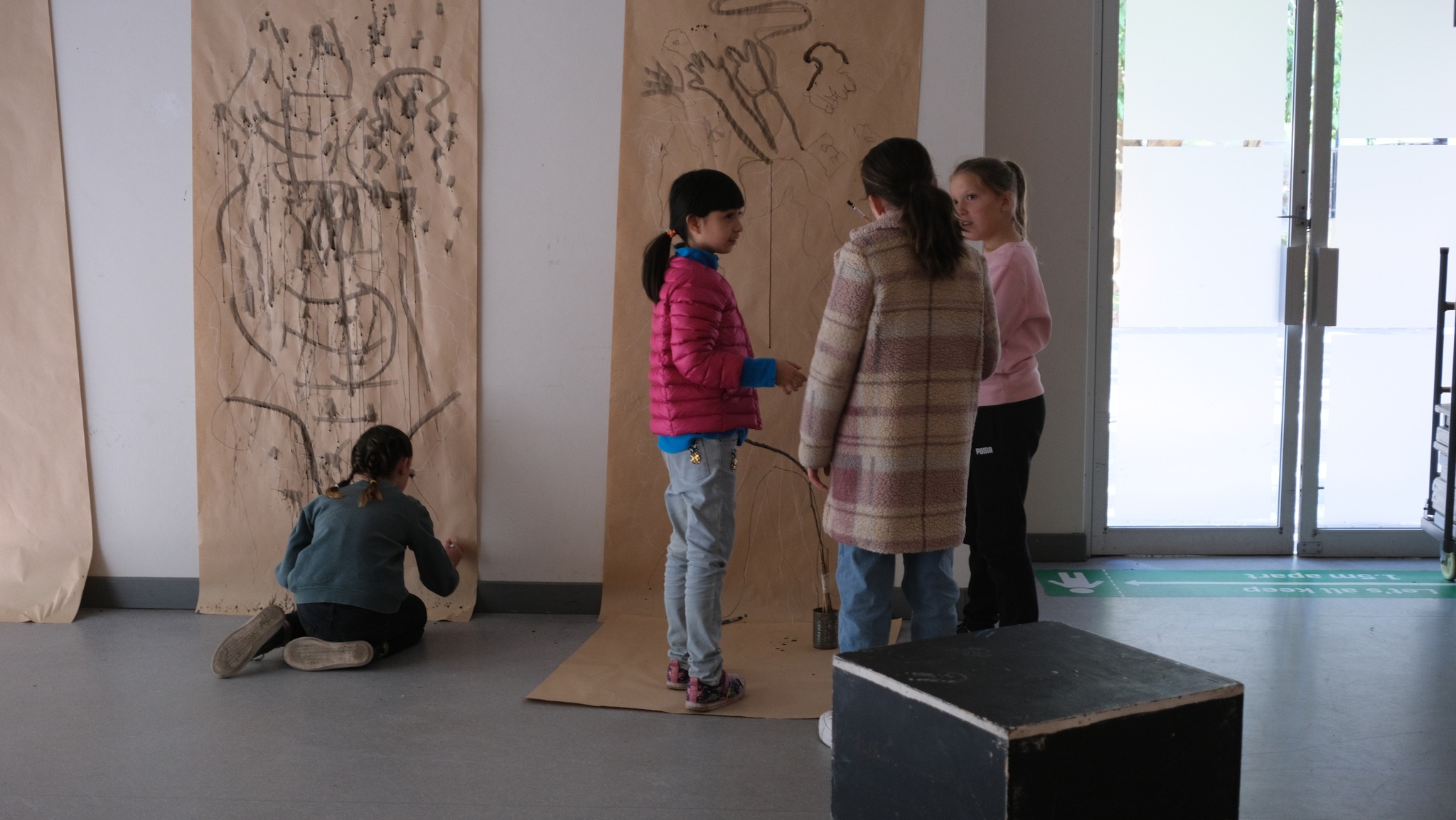 Primary students working collaboratively to draw with ink on large scale paper