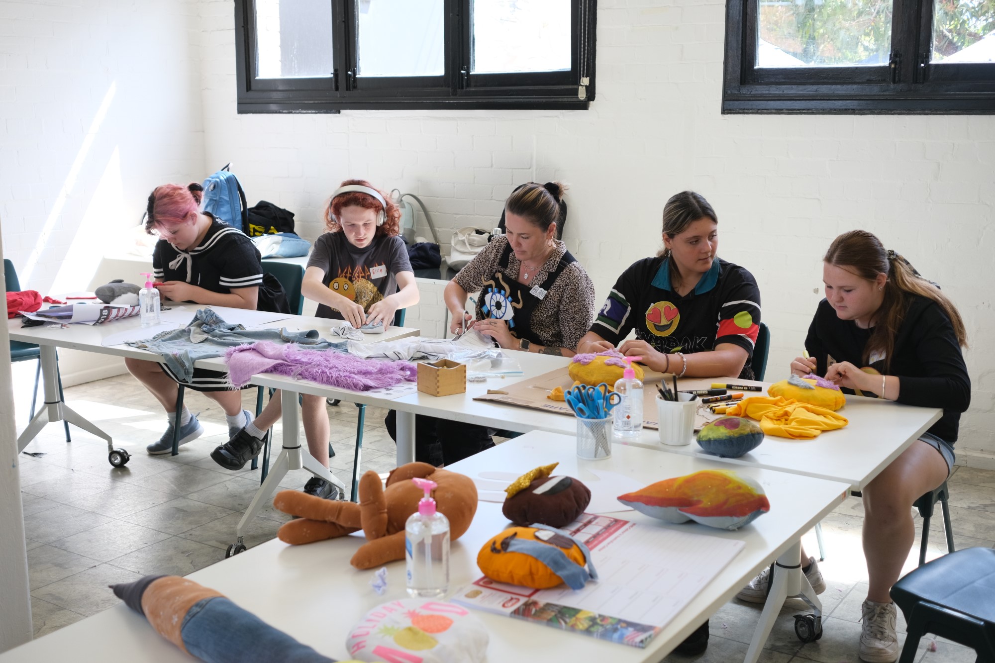 Students seated with visual arts teacher creating soft sculptural artworks from recycled materials