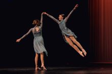 Two Cootamundra High School dancers mid air in pale blue green dresses