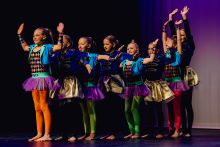 South Wagga Public School dancers in bright coloured costumes posing in a line with their hands raised