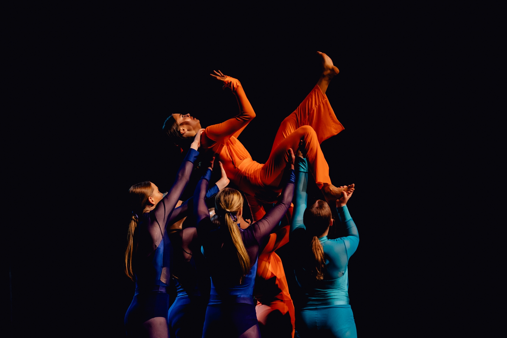 Wagga Wagga High School Senior dancers wearing vibrant chiffon jumsuits holding a student in the air