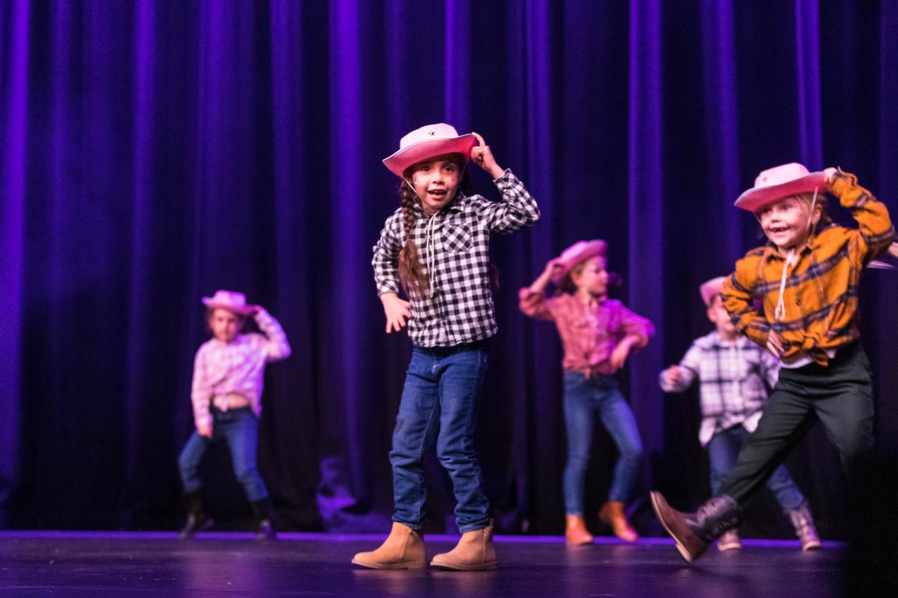 Young dancers on stage dressed in cowgirl and cowboy outfits