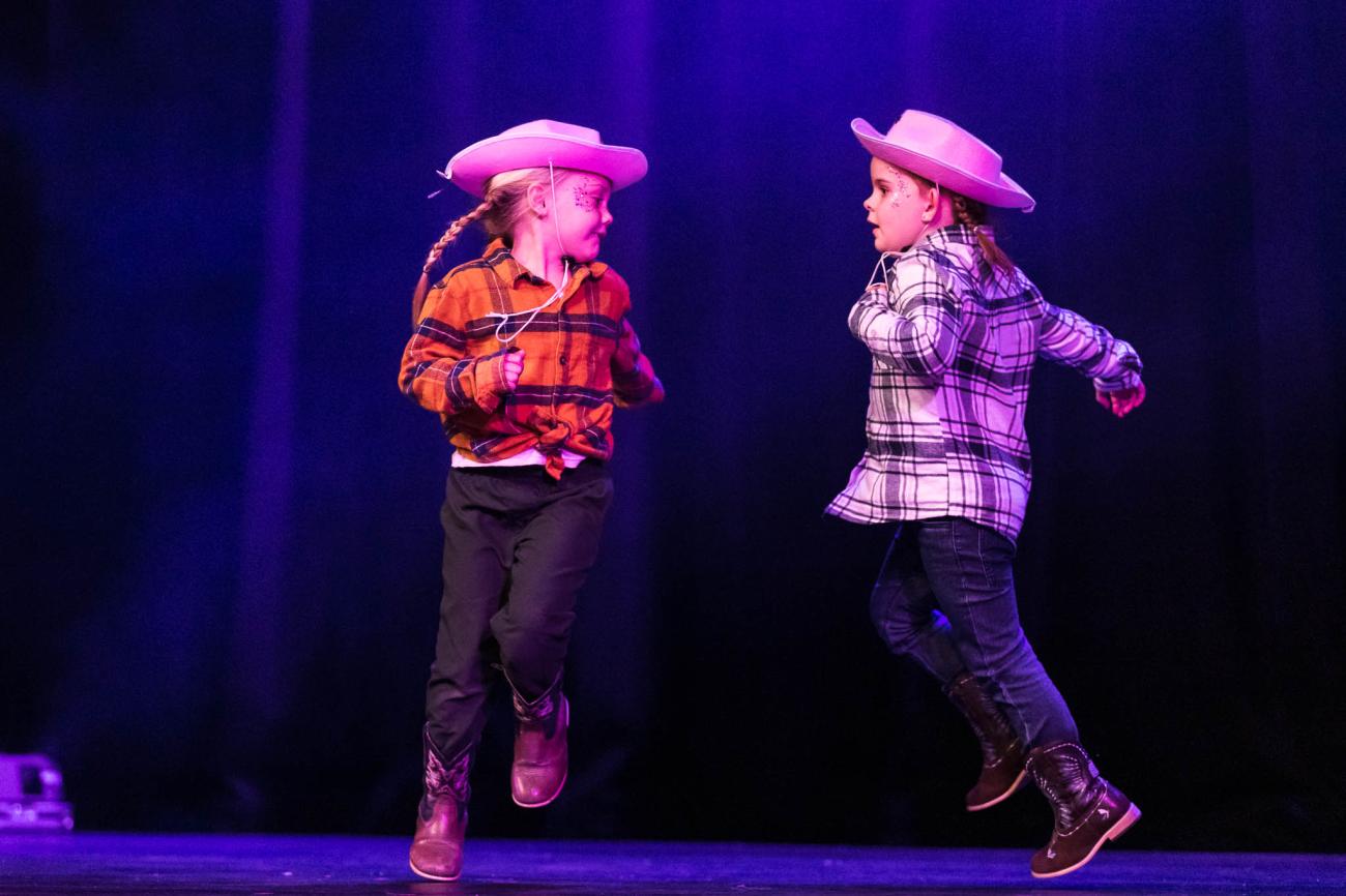 2 young dancers on stage skipping around each other dressed as cowgirls