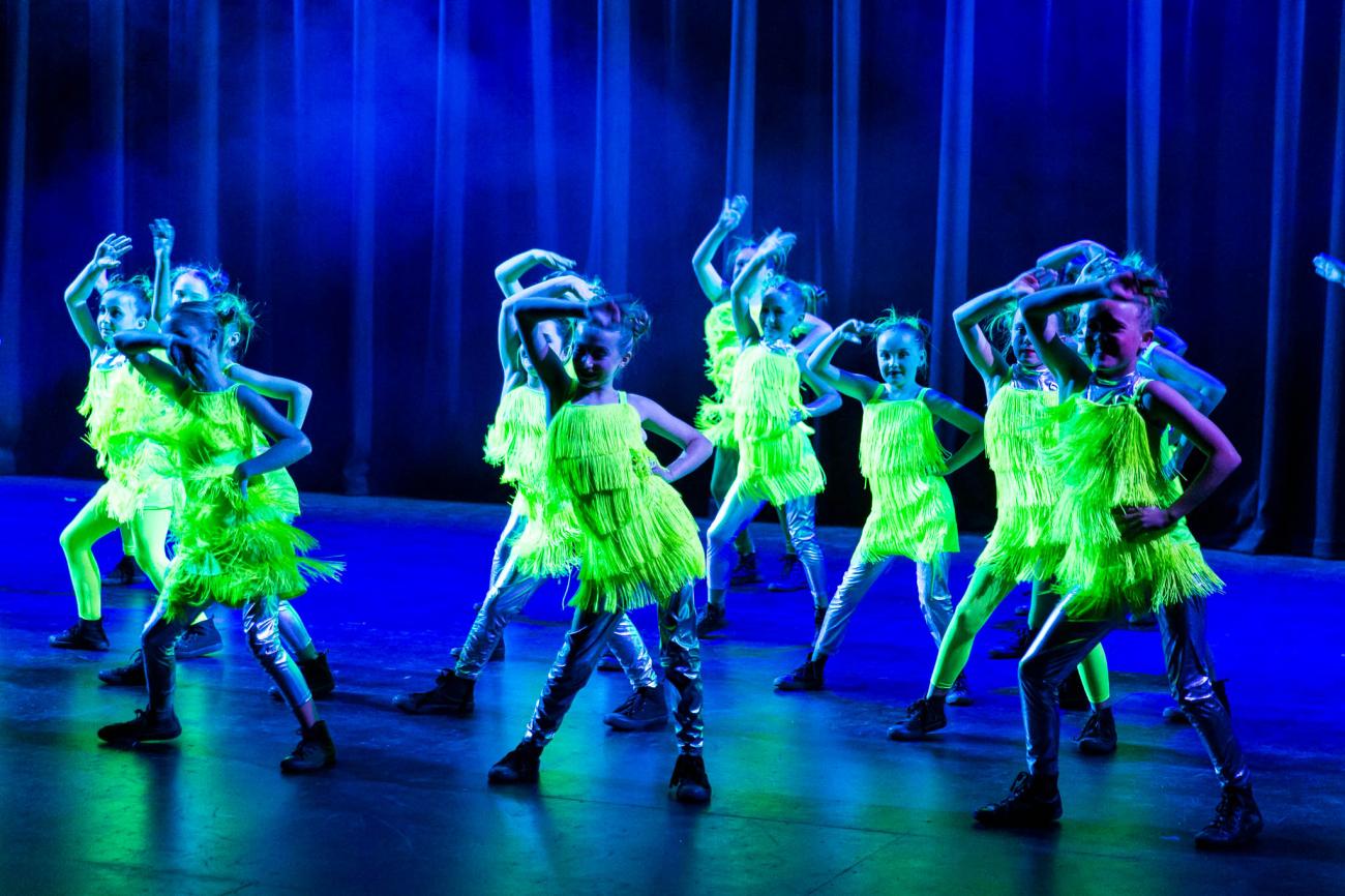 girls in fluro yellow fringe dresses on stage