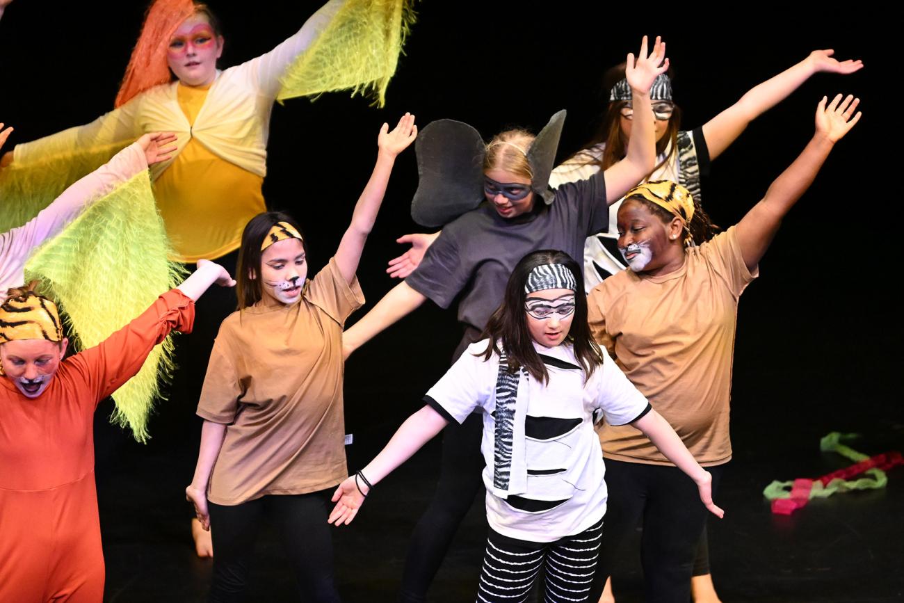 Students on stage in animal costumes from Lion King
