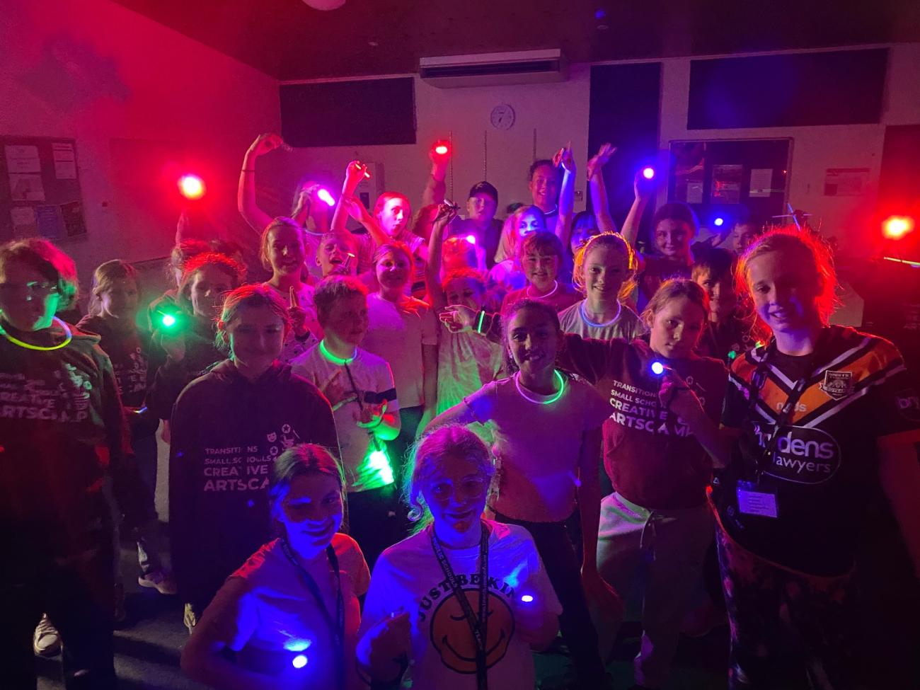 group of students posing for photo at camp disco with coloured lights