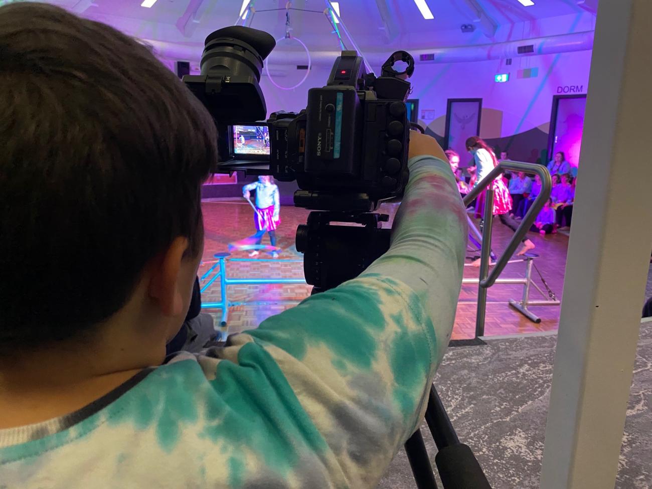 student filming with camera at showcase