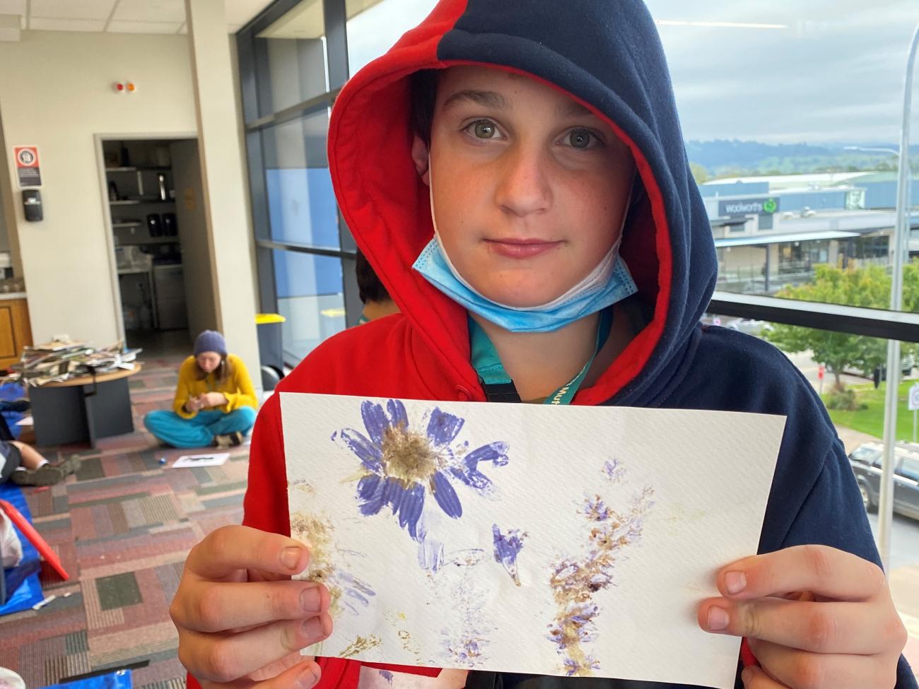 Student holding their completed flower press art