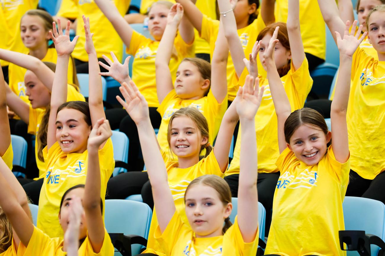 students standing with arms up in yellow tshirts