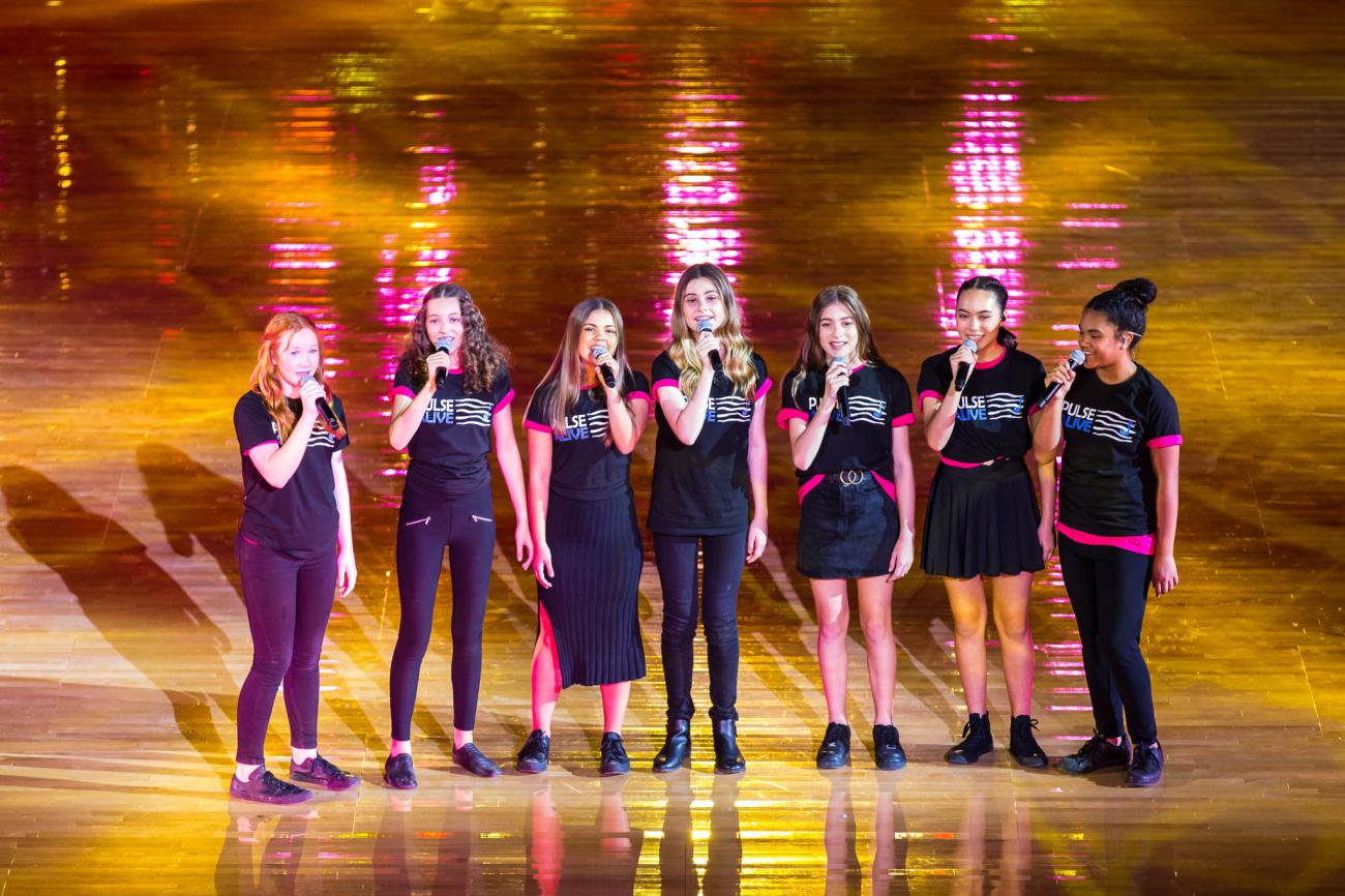 group of 8 vocalists on stage in black