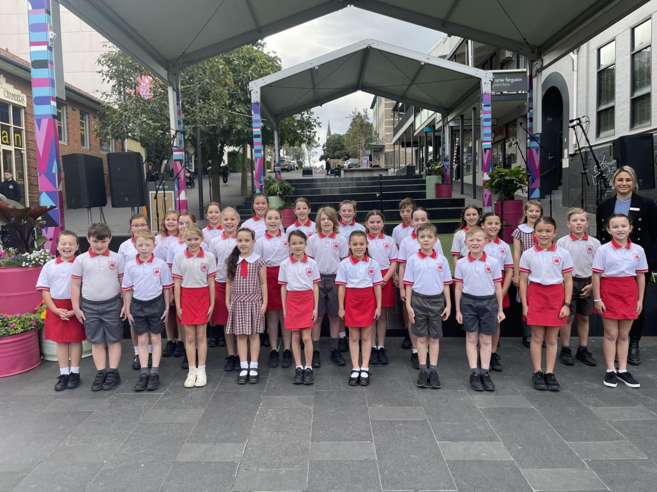 Figtree Public School Junior Choir standing in front of the stage in school uniform for photo