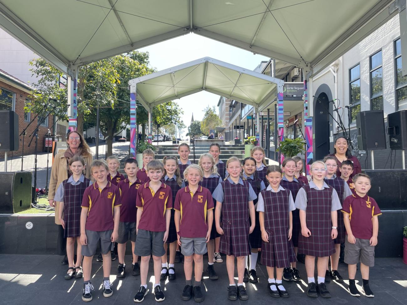 Corrimal East Public School Choir standing in front of the stage in school uniform for photo