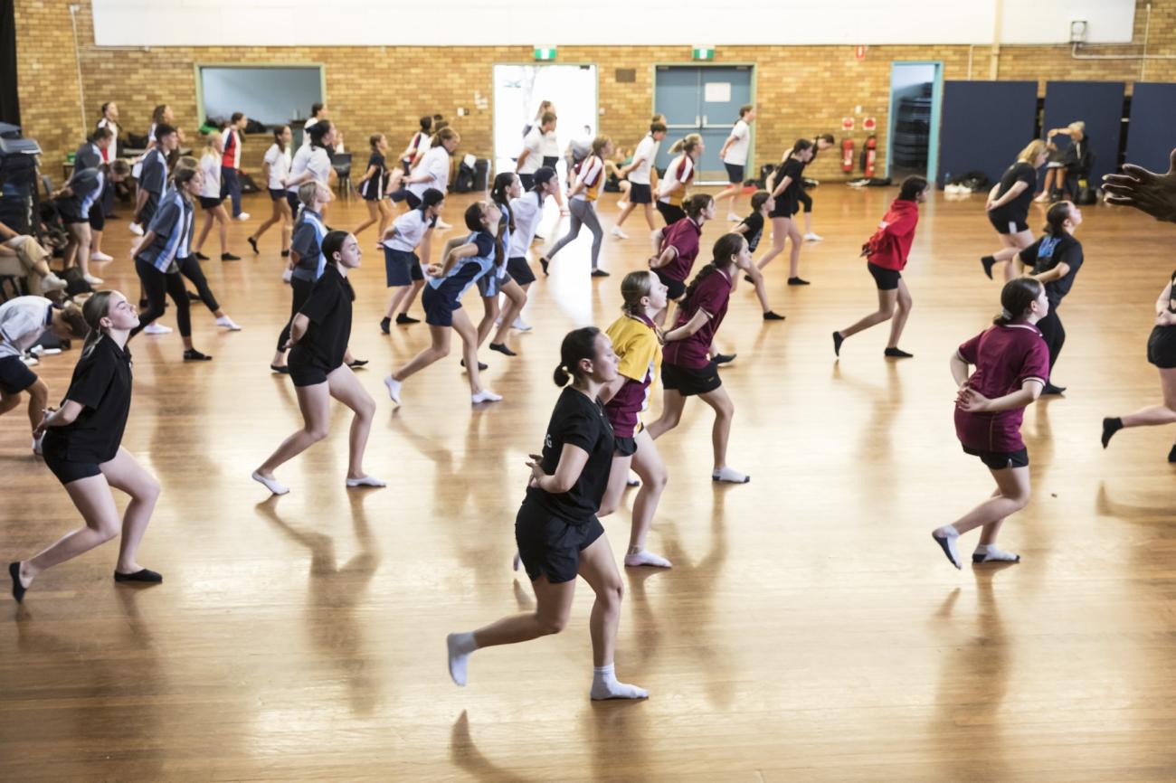 Students dancing with their hands behind their back in a school hall