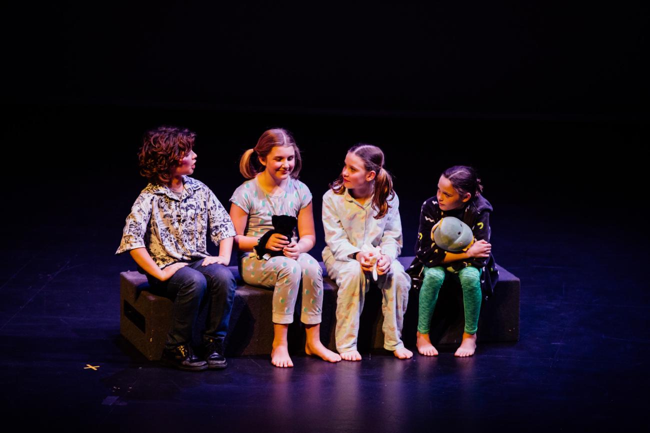 Four primary students sitting on stage