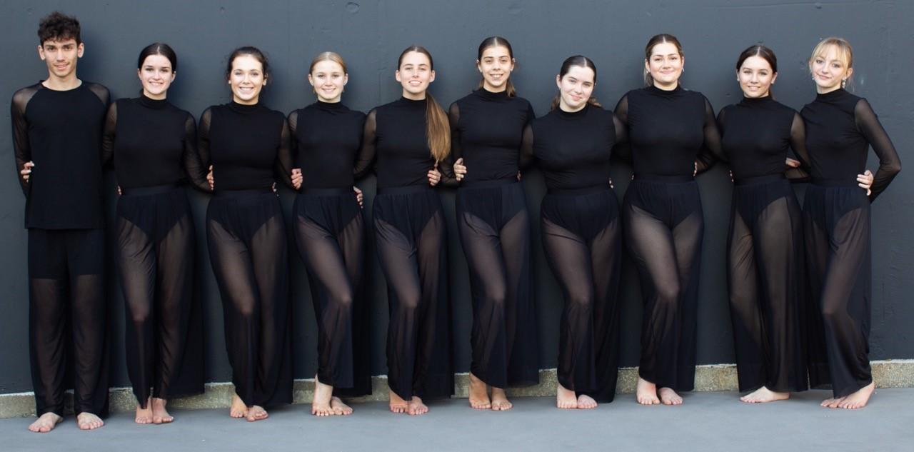 10 students lined up in sheer dark dance costumes