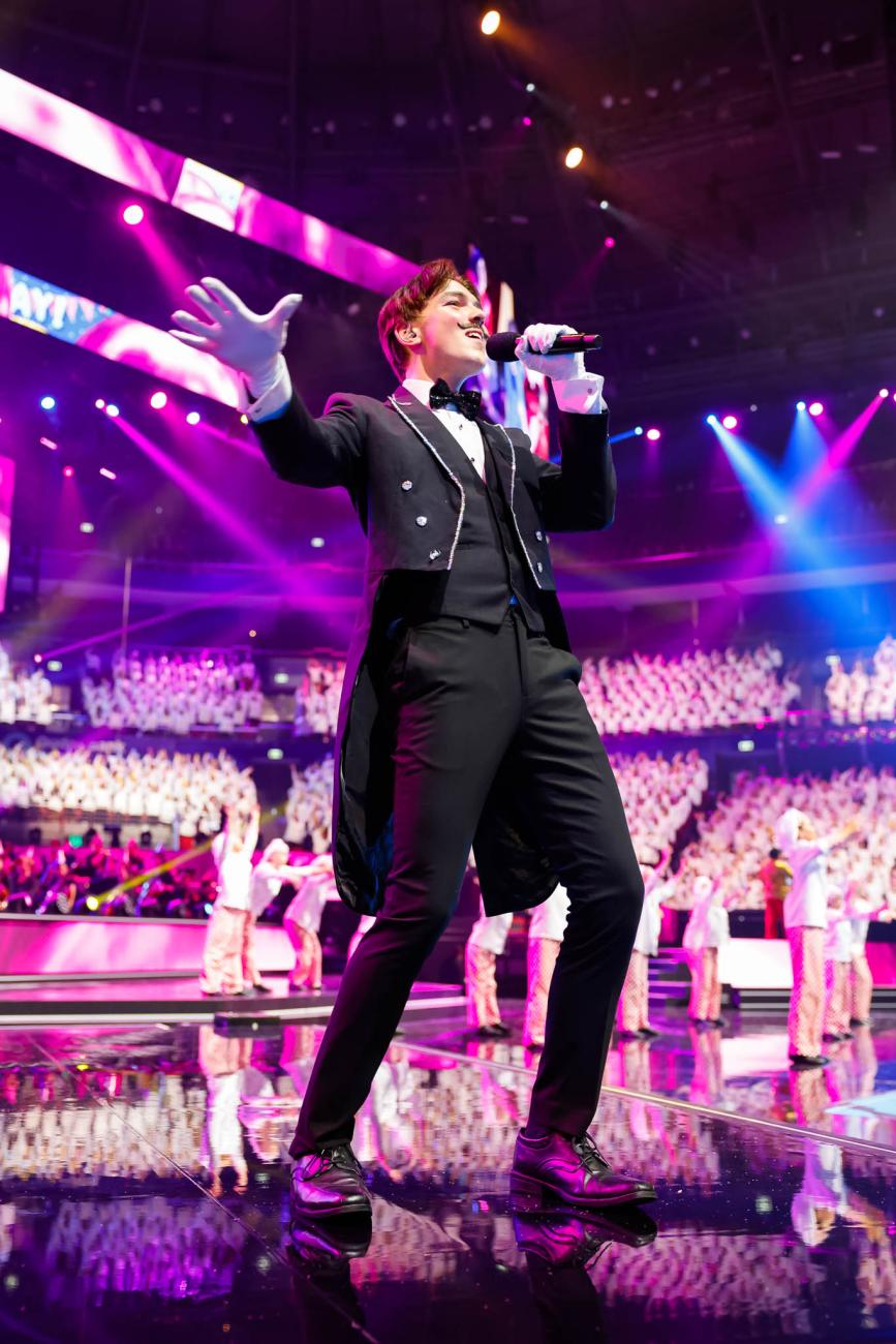 A male singer in black suit with tails, white gloves and a black moustache