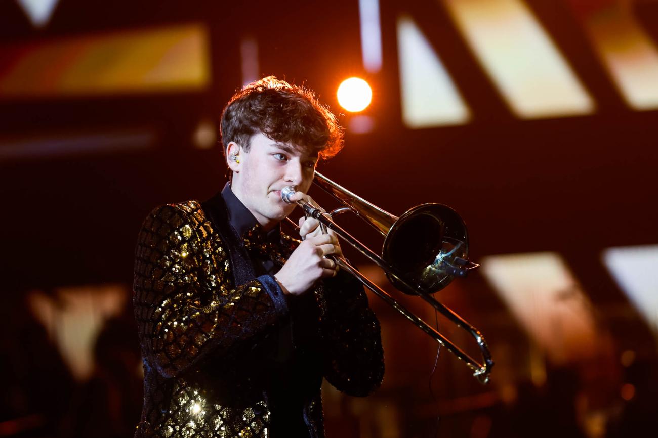 A trombonist wearing a gold sequined jacket