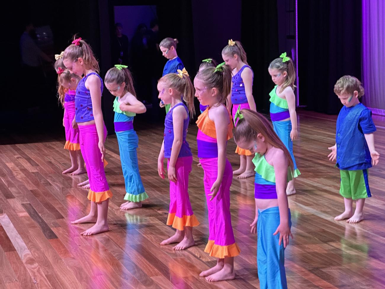 group of young dancers on stage in pink and blue costumes