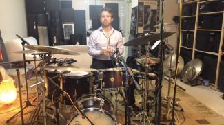 Jason Isaac at his drum kit holding drumsticks.