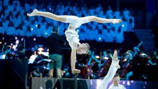 An acrobat in the Schools Spectacular 2019 doing a handstand with their legs in the splits.