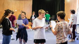 A drama workshop with pairs of students reading scripts to each other.
