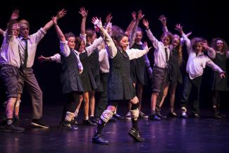 ensemble of students on stage performing at festival.  Wearing school uniforms