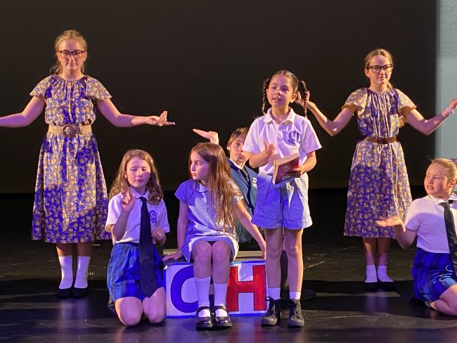 students dressed in school uniform on stage