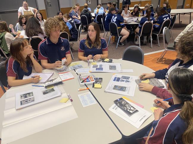 Year 12 students sitting at round tables trialling a variety of art materials