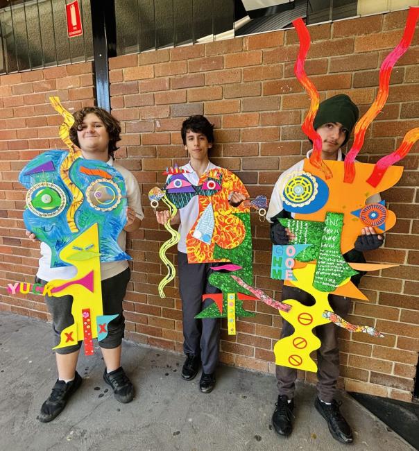 Three boys hold their large, brightly coloured cubist self-portraits.