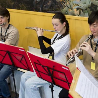 Two students playing flutes and one playing an oboe
