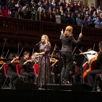 Kate Miller-Heidke singing in front of an orchestra at Sydney Town Hall with Elizabeth Scott conducting for In Concert